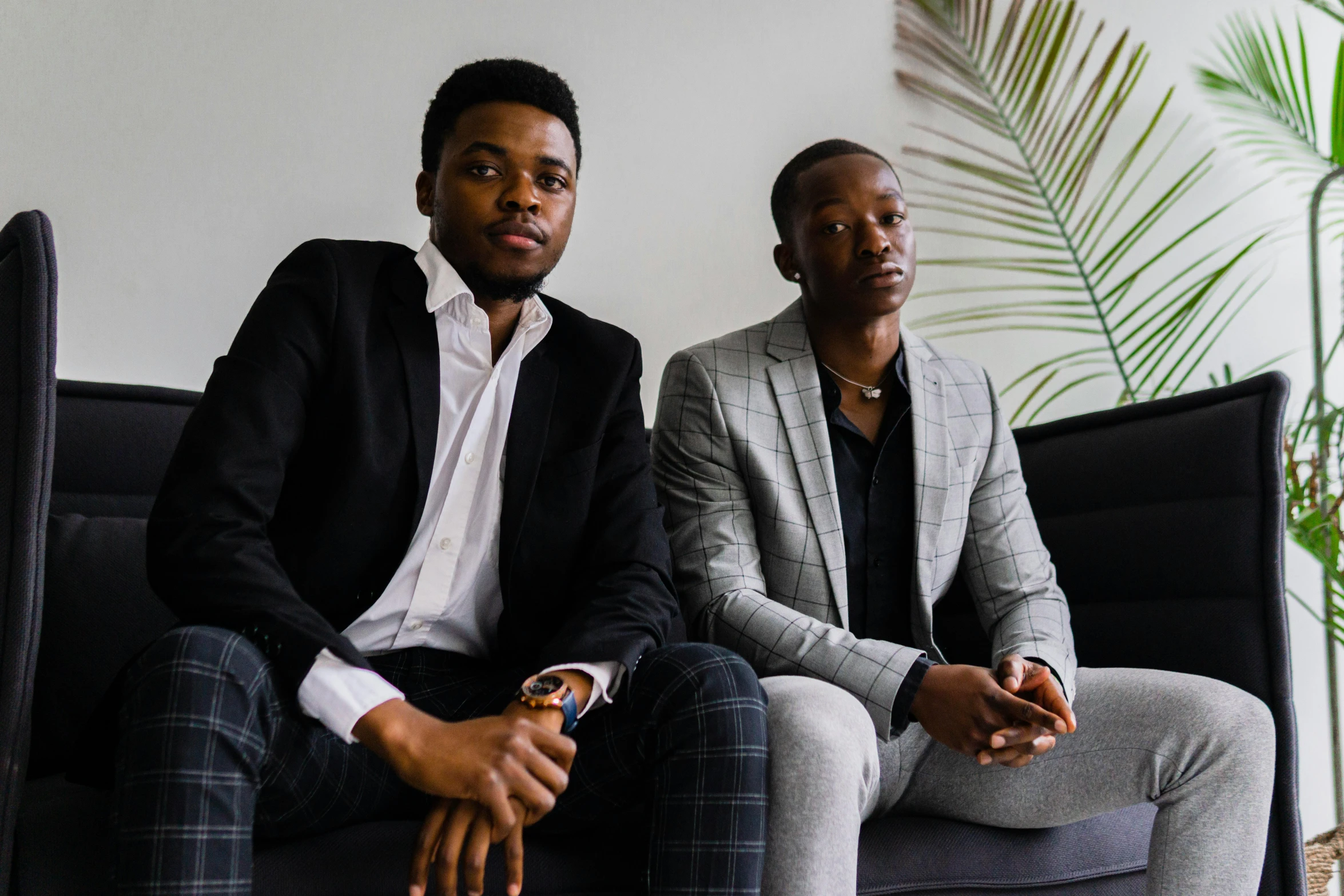 two men sit on a chair in suits