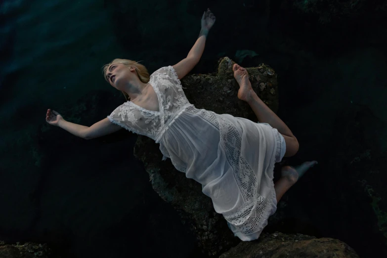 a young lady is lying on the rock while floating