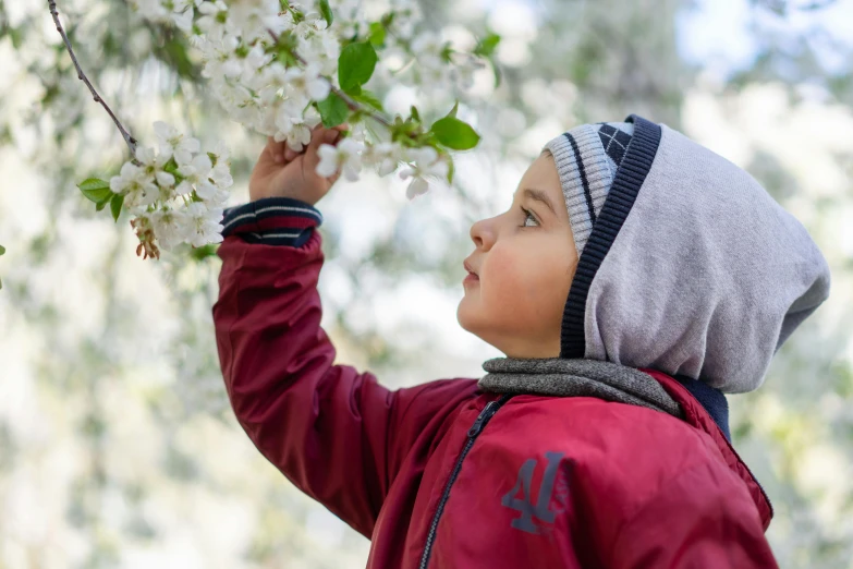 a little  wearing a hat in front of flowers