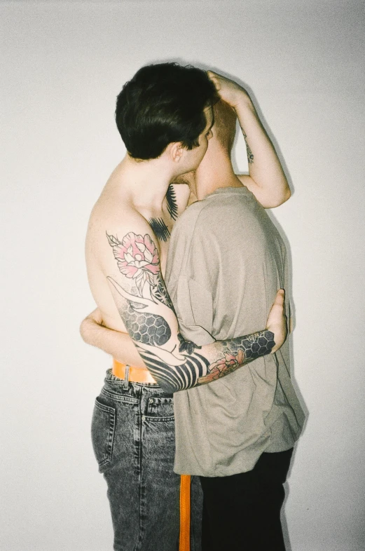 two people hugging each other with one wearing tattoos