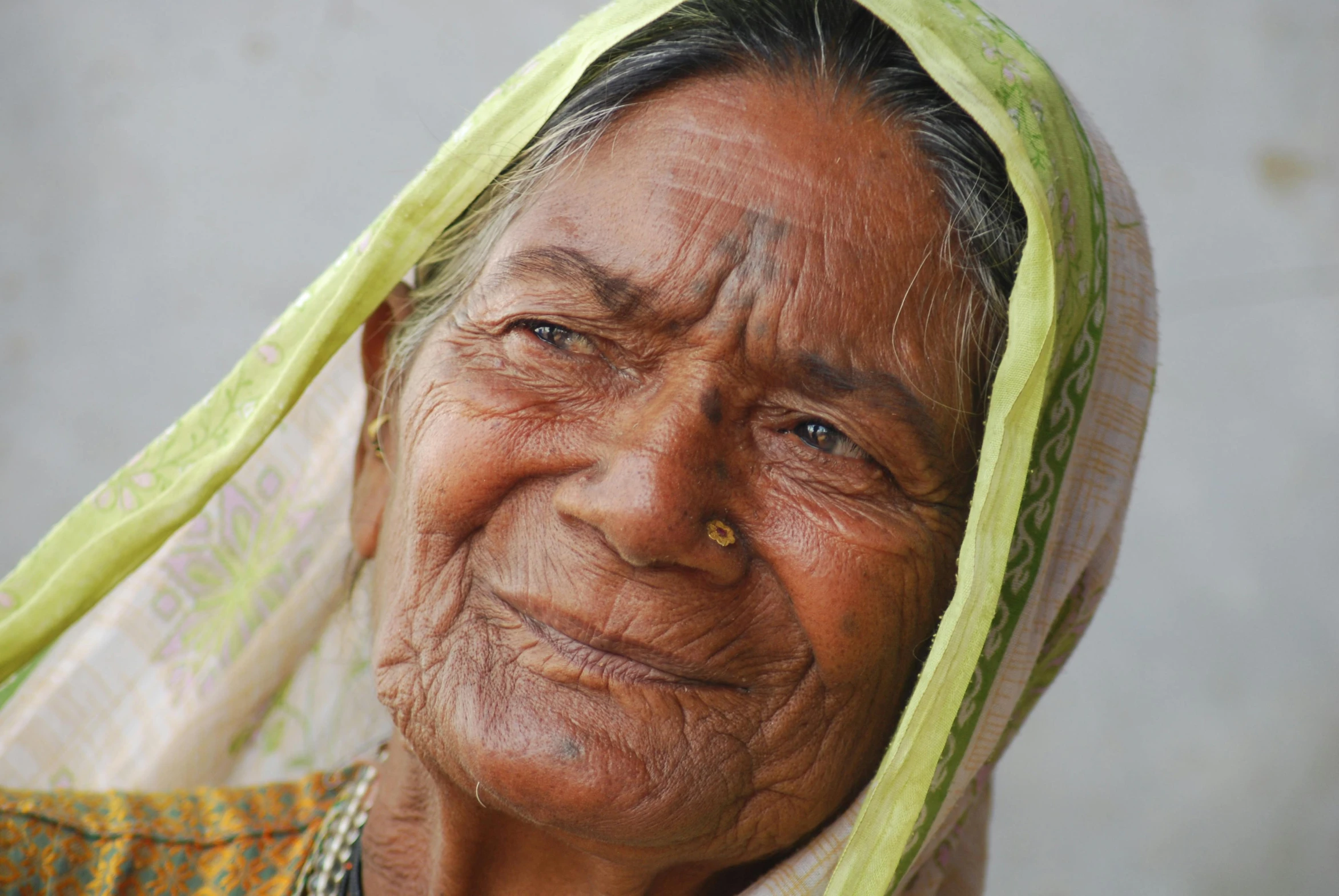 a old lady that is wearing a green scarf