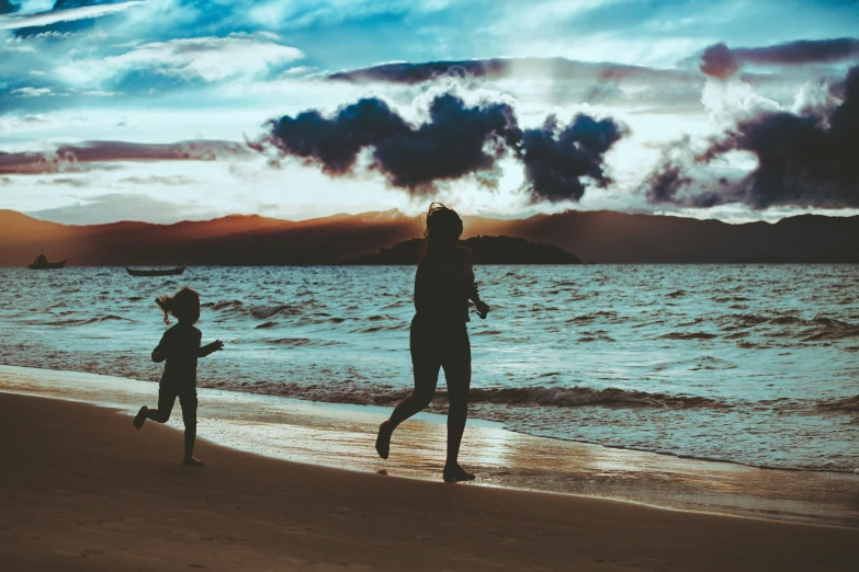 a boy running along a beach towards the water