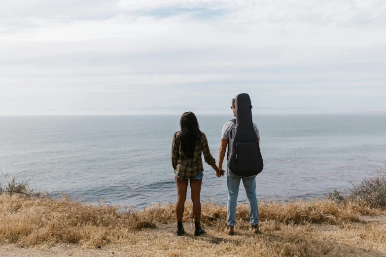 two young people are standing near the water