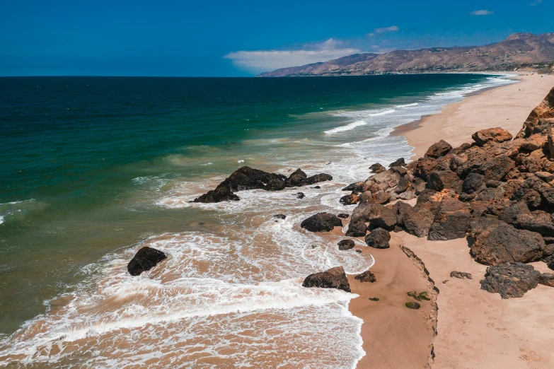 two large rocks are on the shoreline of a beach