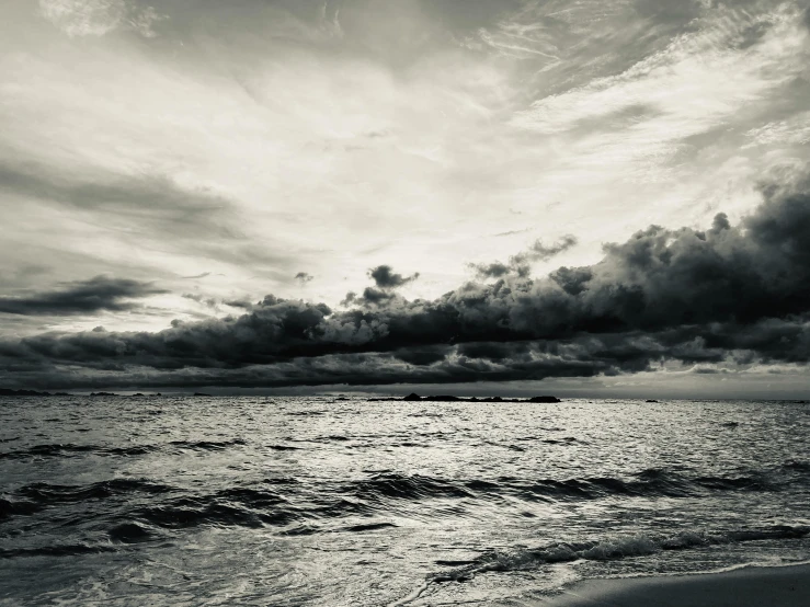 a cloudy sky and dark clouds over an ocean