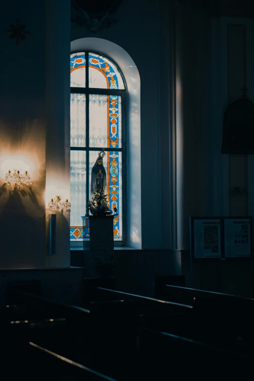 a church's stained glass window behind a statue of jesus