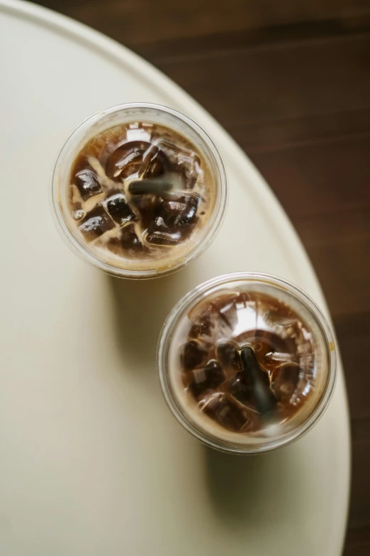 two cups of ice coffee with a spoon and a plastic cup on the side