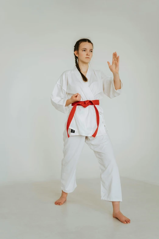 a young woman wearing a karate outfit standing on her feet