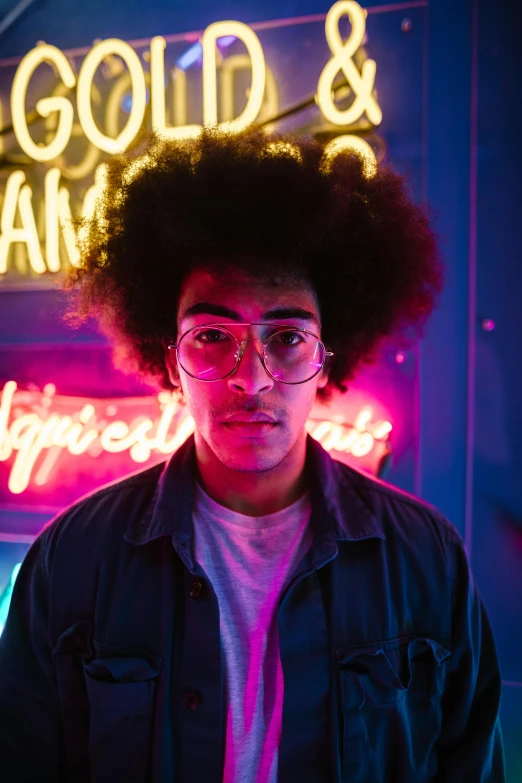 a man with an afro standing in front of a neon sign