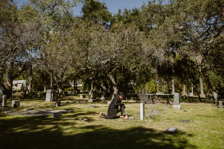 an cemetery with a woman kneeling down in front of graves