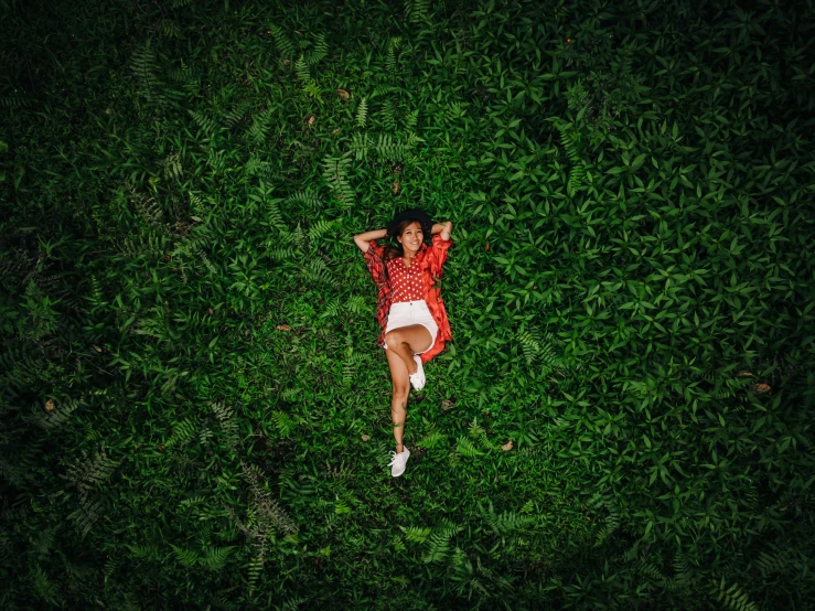 the top view of a woman lying on her back in green grass