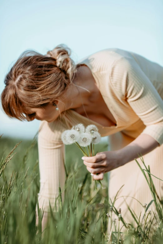 woman with flower in hand standing in grass