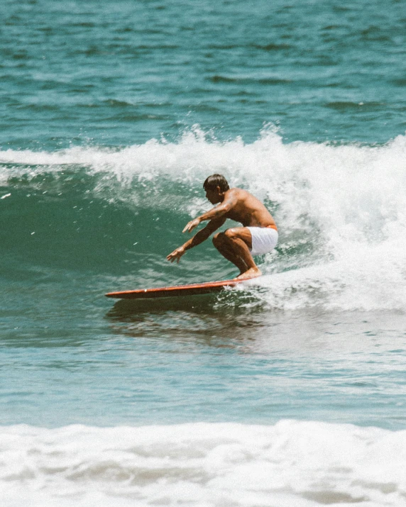 a man in trunks surfing on a wave