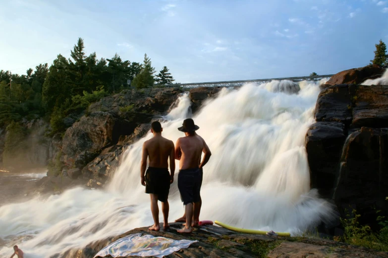 a couple of men standing next to a waterfall