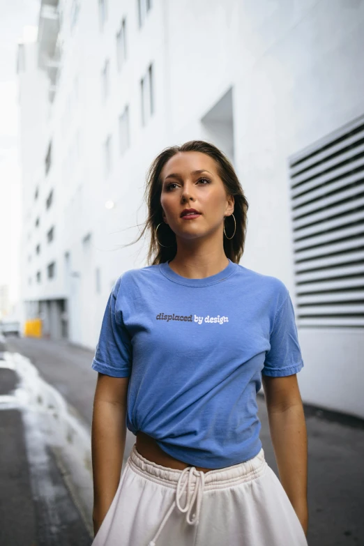 a girl standing outside while wearing a blue shirt