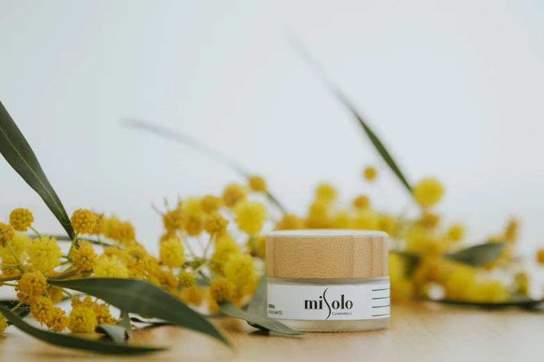 a close up of a jar of essential eye cream and yellow flowers