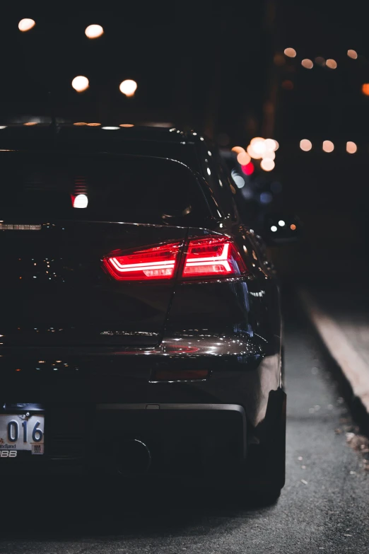 a black car parked at night next to a street light