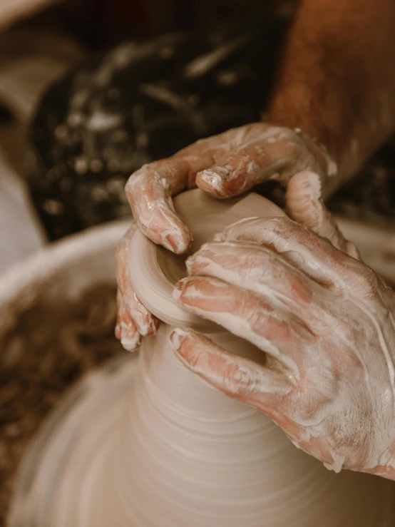 the person's hands are making pottery on a potters wheel