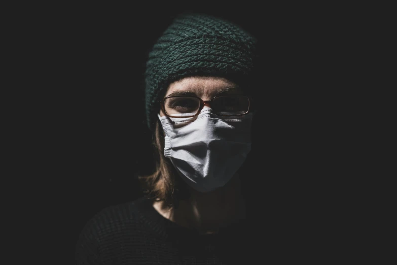 a woman wearing a green knitted hat with a white face mask