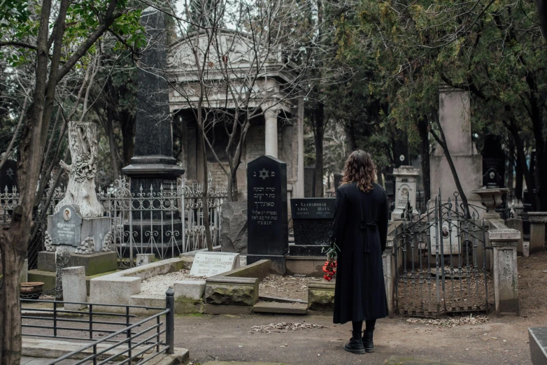 there is a woman that is standing outside at the grave