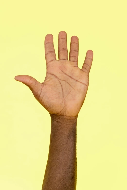 an outstretched hand up in front of a yellow background