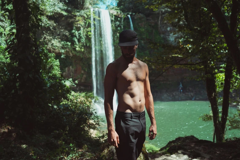 a man walks away from the waterfall and in front of the lake