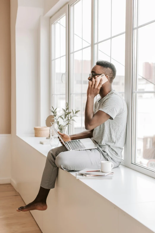 man sits on the windowsill with his cell phone