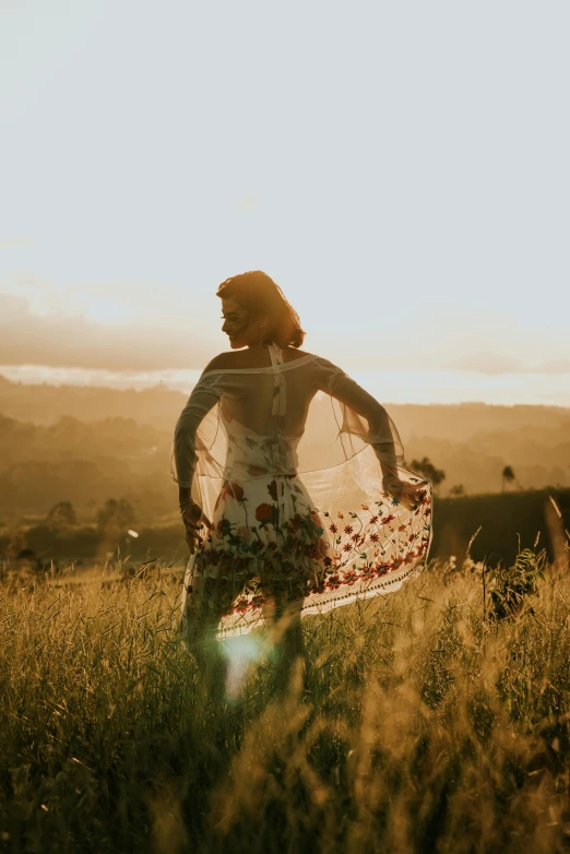 a woman standing in tall grass in the sun