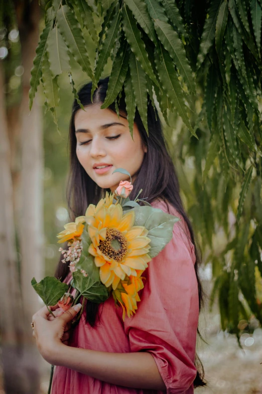 a girl in a dress holding onto flowers and smelling her eyes