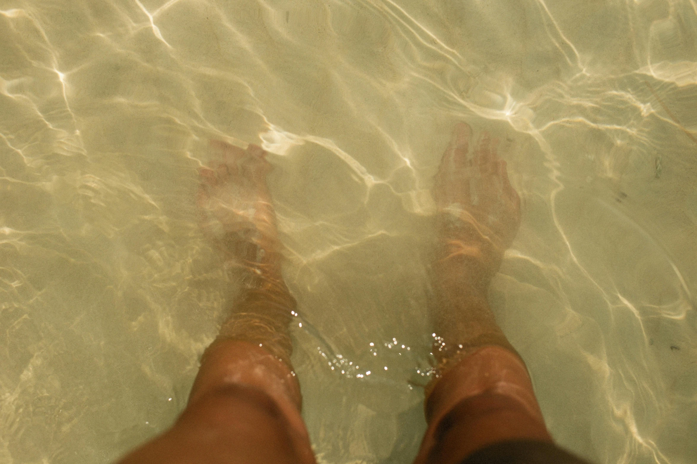 the person is standing in clear water looking down