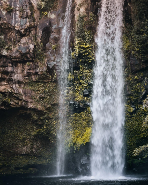 a waterfall on the side of a lush green hillside