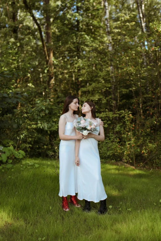 two women in white dresses and red boots hold bouquets