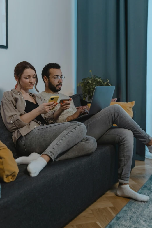 two people on a couch reading on their laptops