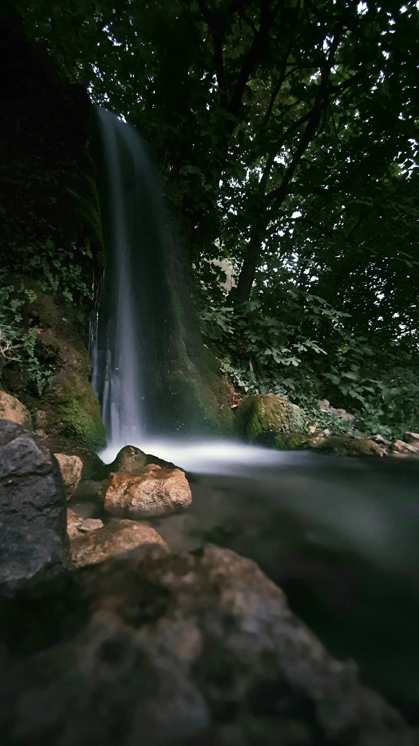 a waterfall in the middle of a stream surrounded by rocks