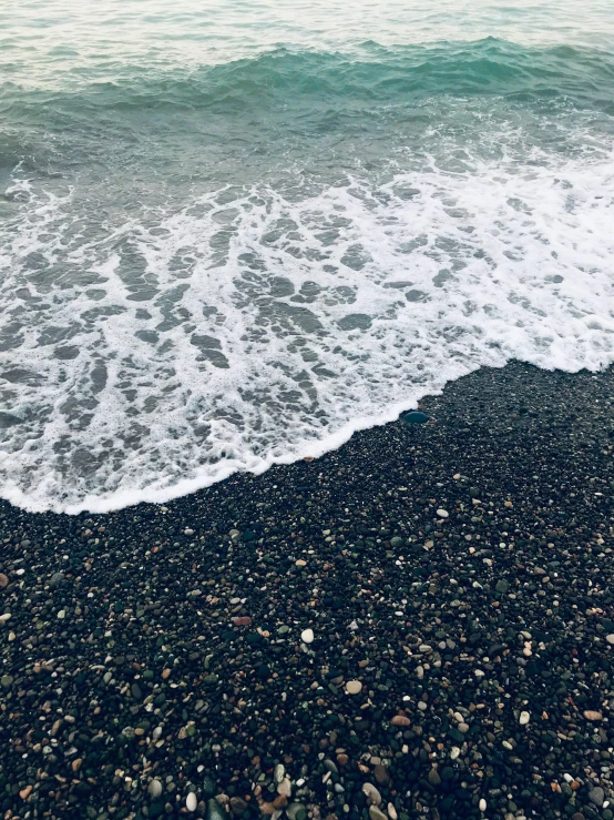 a black beach with waves crashing on it