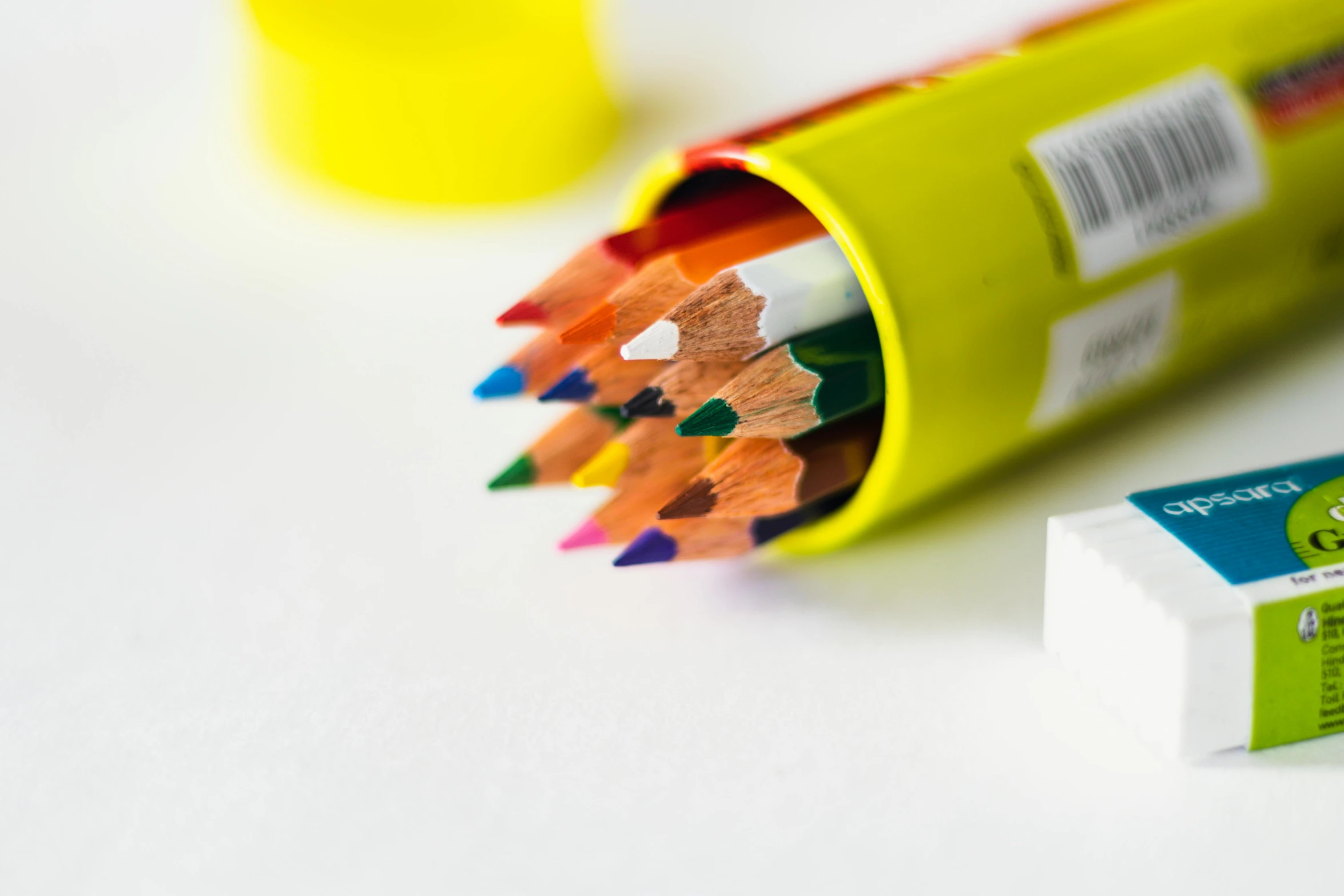 three different pencils laying next to a tube of colored pencil