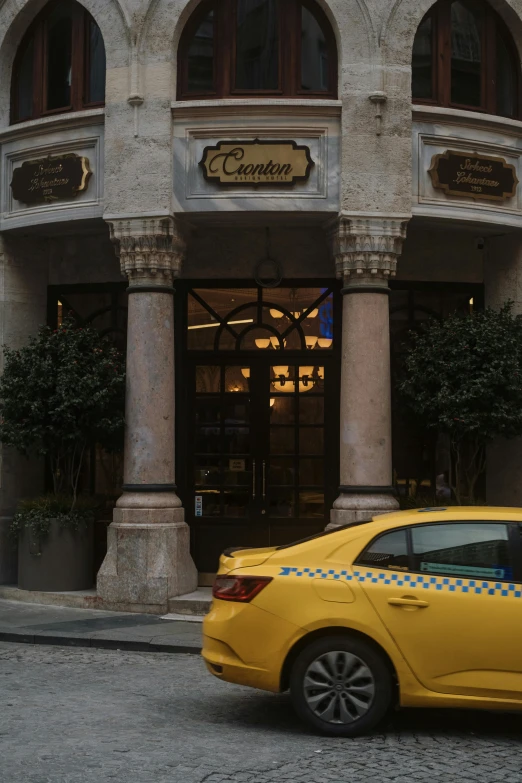 a yellow taxi cab drives past a restaurant