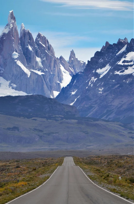 long straight road running through the plains with mountains in the background