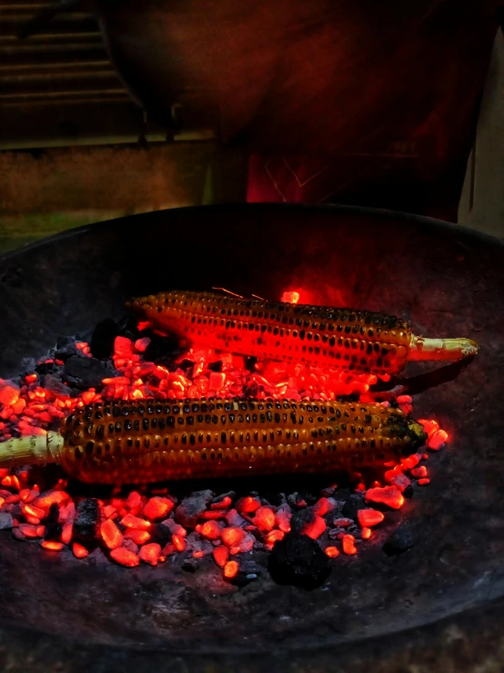 there are two corns on the grill, some lit and another burning