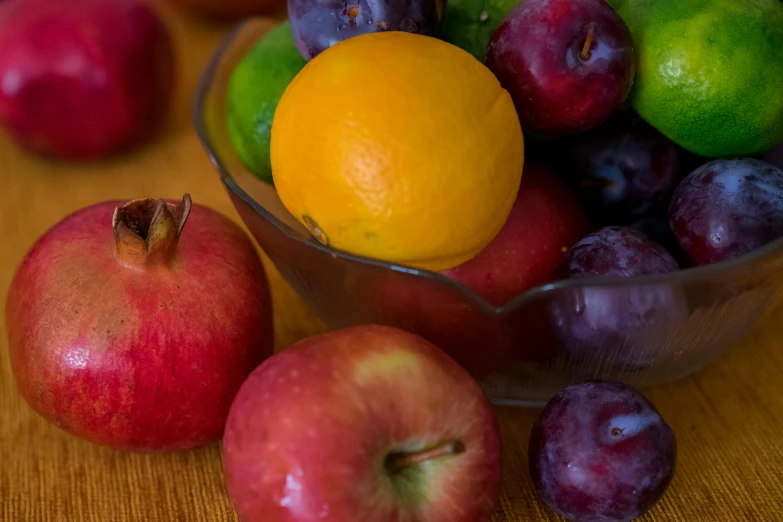 various fruits in a glass bowl with one fruit still in it