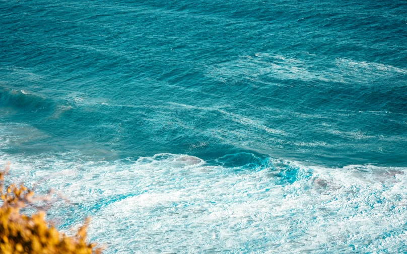 a wave rolls in to shore and a surfboarder is on the waves