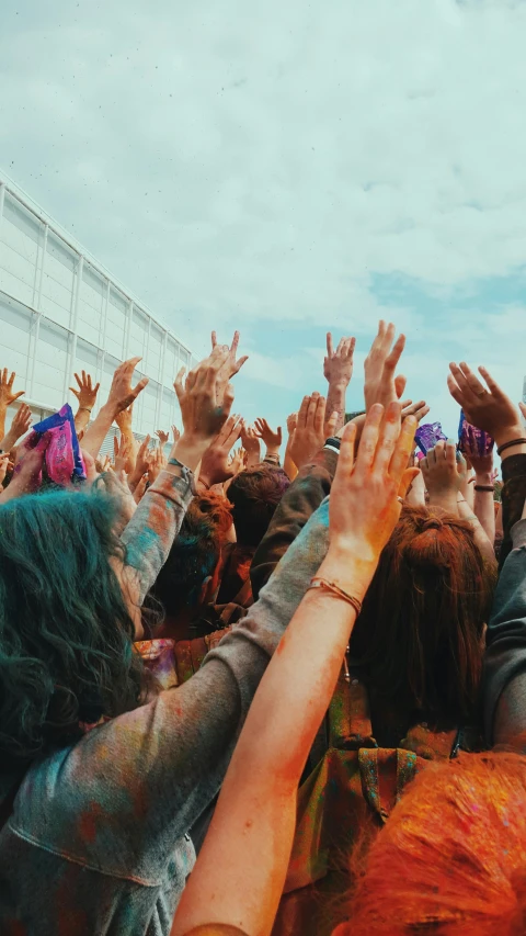 a group of young people are waving their hands in the air