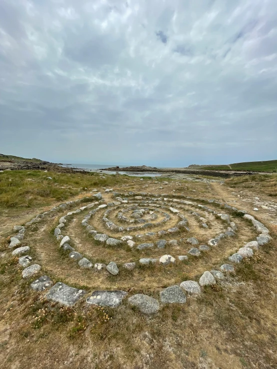 a circular shape made from small rocks is pictured in the middle of a grassy field