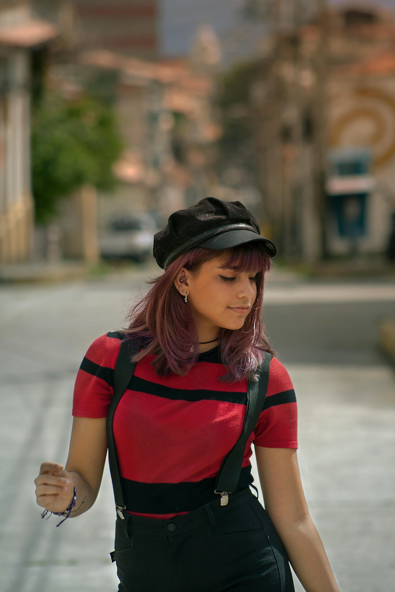 a girl with short hair wearing suspenders, an overalls and a black hat