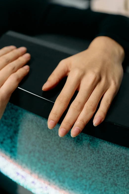 person's hand resting on a black surface holding a knife