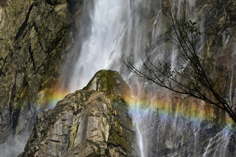 a waterfall has a rainbow in it surrounded by trees