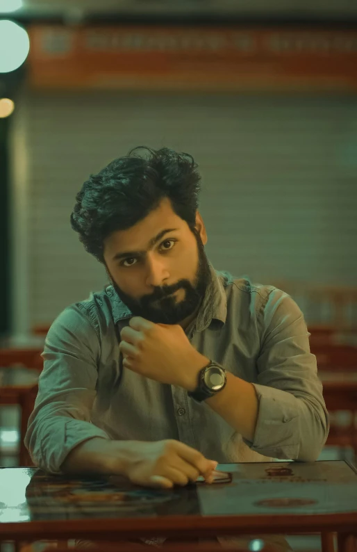 a man looking over his watch while seated at a table