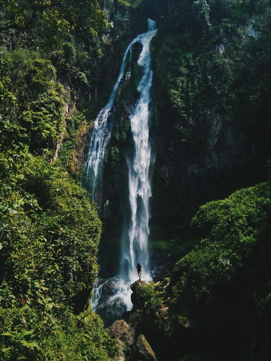 two people standing at the bottom of a waterfall