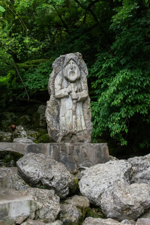 a stone statue is standing among some rocks