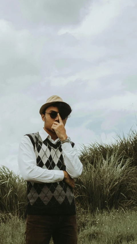 a man wearing sunglasses and vest is holding a cellphone to his ear